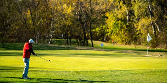 Голфър играе на Golf Club Ada в Белград, Сърбия – удар към грийна сред есенни дървета